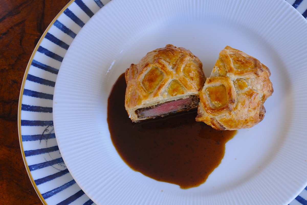 Beef Wellington from a private chef in the Algarve, sliced to show pink beef fillet and truffle jus